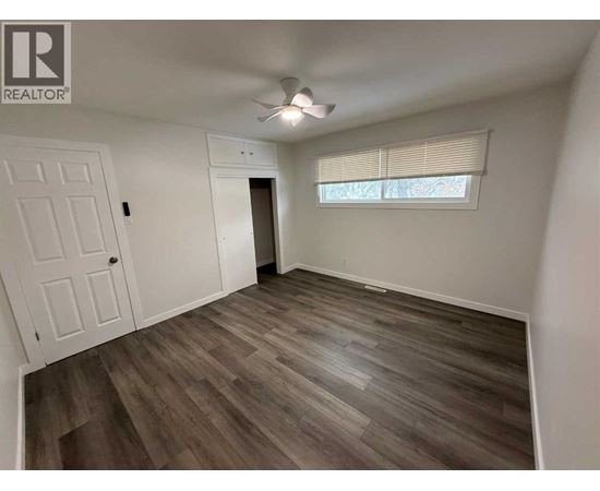 A room with a wooden floor and a window with blinds.