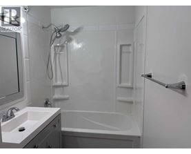 A white bathroom with a sink, mirror, and bathtub.