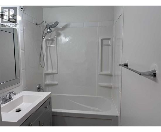 A white bathroom with a sink, mirror, and bathtub.
