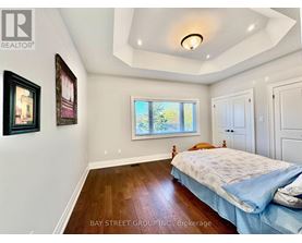 A bedroom with a bed, a window, and a painting on the wall.