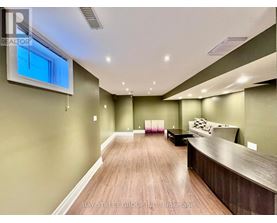 A spacious room with wooden flooring and a large window.