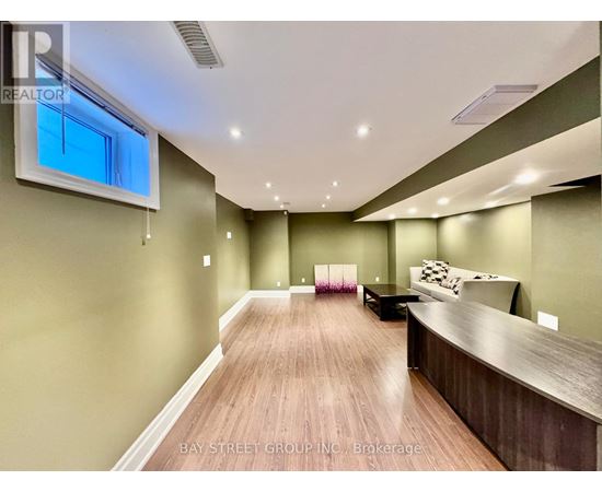A spacious room with wooden flooring and a large window.