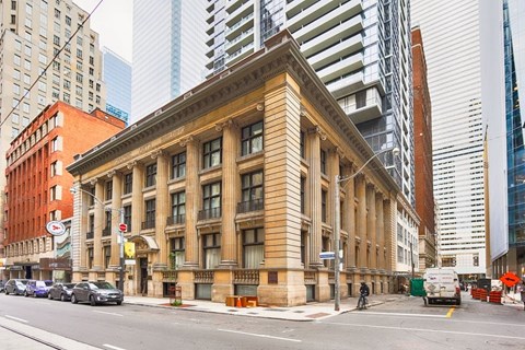 A large, old-fashioned building with a brown facade is situated on a street corner.