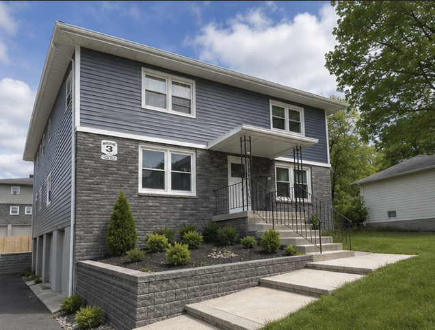 A grey house with a black iron railing on the porch.