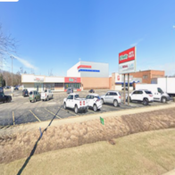 Cars are parked in a lot in front of a store.