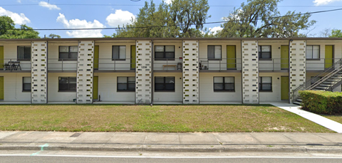 Apartment building with balconies and greenery in front.