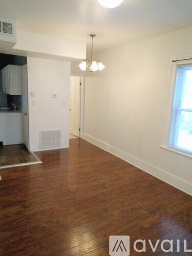 A room with wooden floors and a window on the right side.