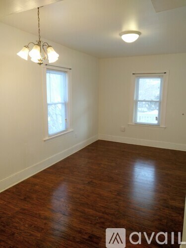 A room with wooden floors and two windows.
