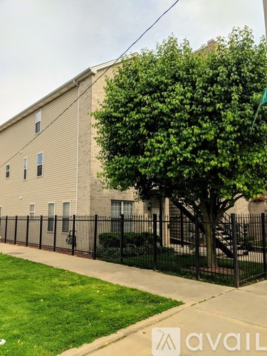 A tree in front of a building with a fence around it.