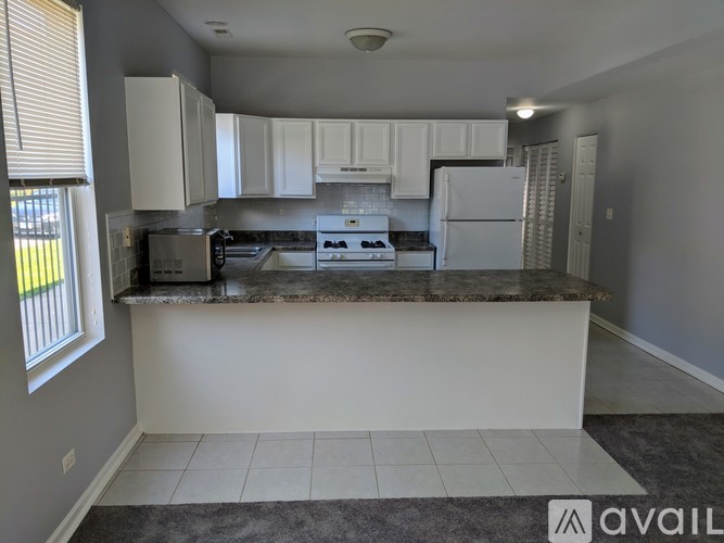 A kitchen with white cabinets and a marble countertop.