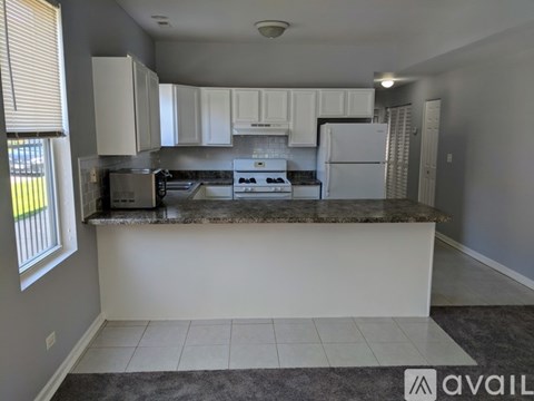 A kitchen with white cabinets and a marble countertop.