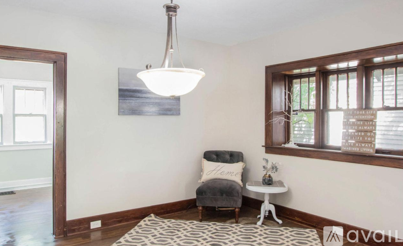 A living room with a grey chair and a white side table.