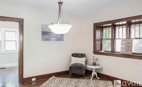 A living room with a grey chair and a white side table.
