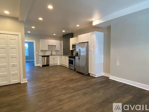 A spacious kitchen with white cabinets and a wooden floor.
