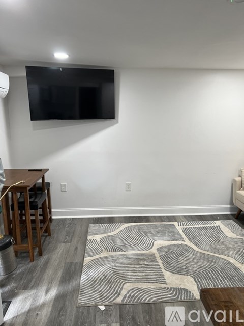 A living room with a tv mounted on the wall and a wooden table with chairs.