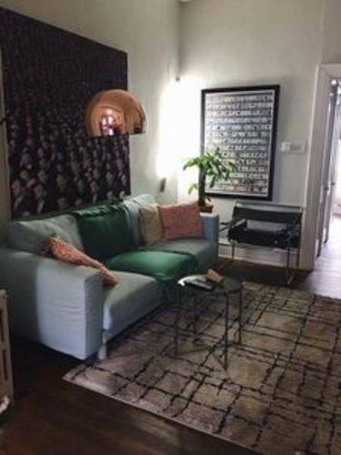 A living room with a green couch and a black and white poster on the wall.
