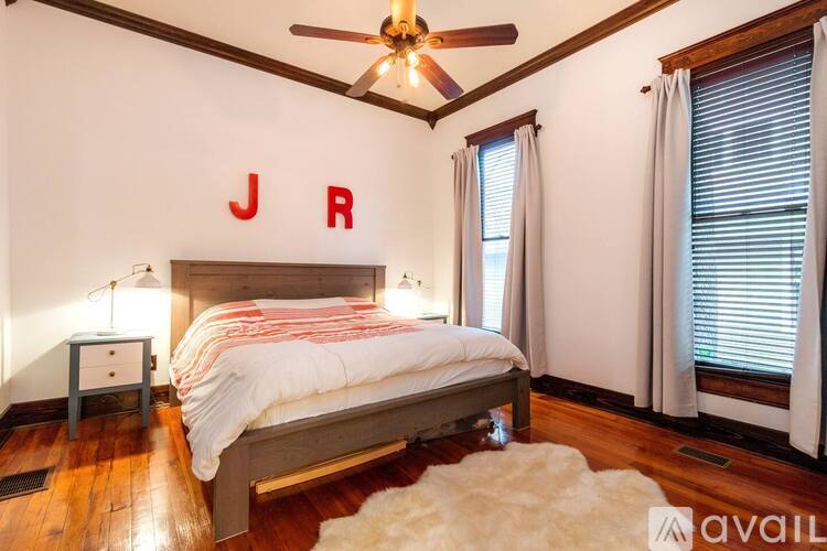 A bedroom with a bed, a ceiling fan, and a nightstand with a lamp.