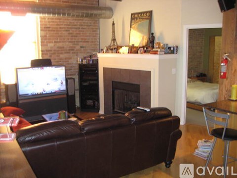A living room with a brown leather couch and a fireplace.