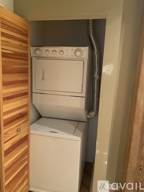 A white dryer is in a small space next to a wooden door.