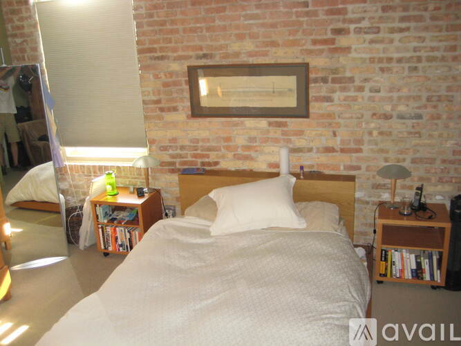 A bedroom with a brick wall and a bed in the center.