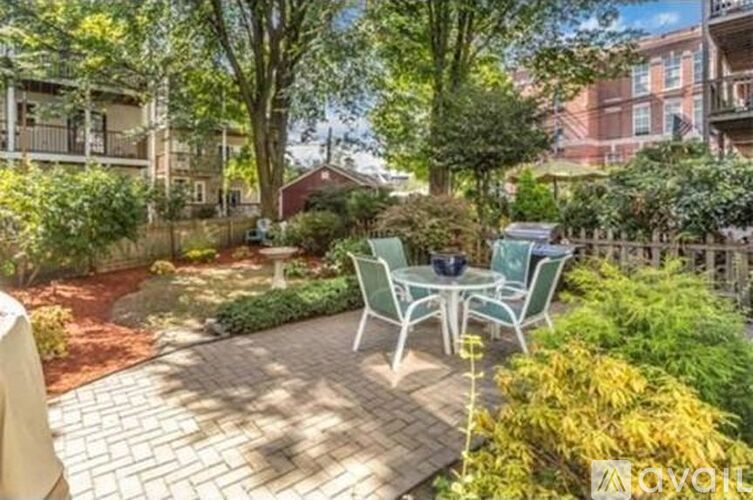 A patio with a table and chairs surrounded by greenery.