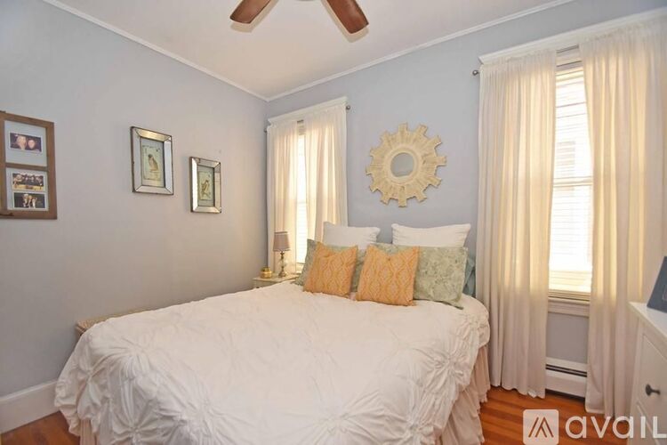 A bedroom with a white bed and a ceiling fan.