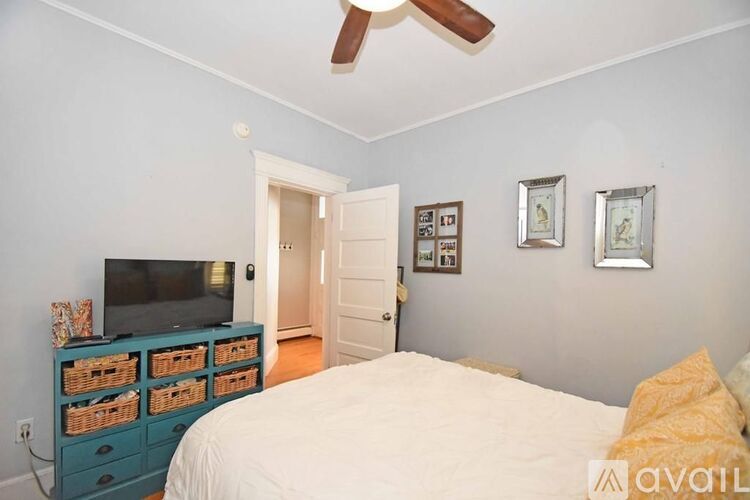 A bedroom with a bed, dresser, and ceiling fan.