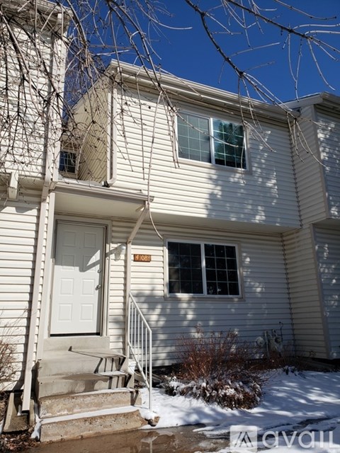 A house with a white door and a window is shown with snow on the ground.