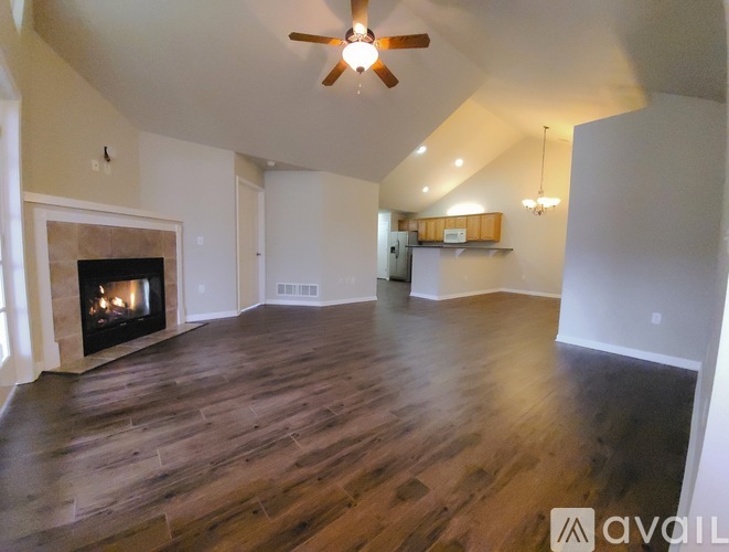A spacious living room with a fireplace and wood flooring.