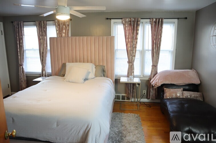 A bedroom with a large bed and a window with curtains.