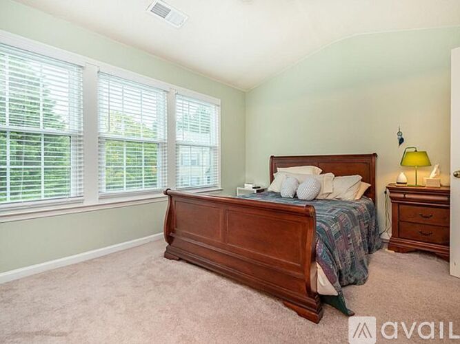 A bedroom with a bed, nightstand, and window with blinds.