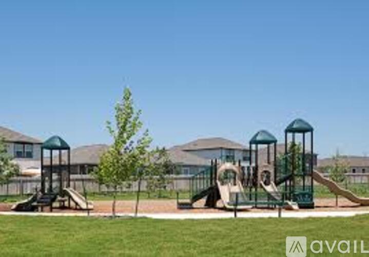 A playground with a green slide and a tree in the foreground.