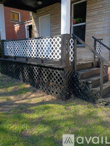 A wooden porch with a lattice design and steps leading up to a door.