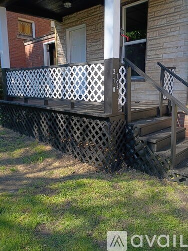 A wooden porch with a lattice design and steps leading up to a door.