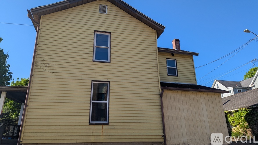 A two-story house with a yellow exterior and a small window on the second floor.