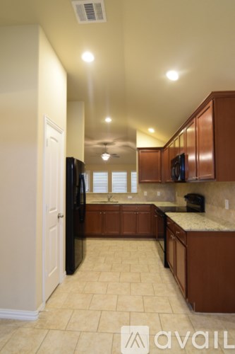 A kitchen with brown cabinets and a black refrigerator.