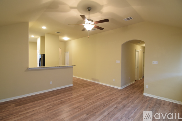 A spacious room with a ceiling fan and wooden flooring.