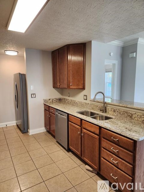 A kitchen with brown cabinets and a granite counter top.