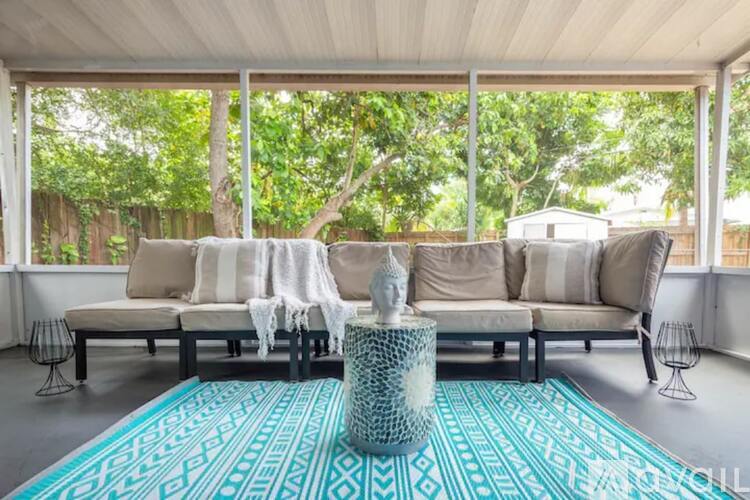 A living room with a white sofa and a blue patterned rug.