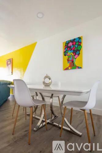 A dining room with a white table and chairs.