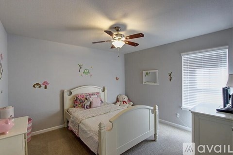 A white bedroom with a bed, dresser, and a ceiling fan.