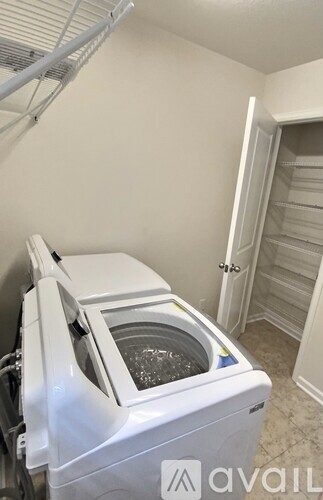 A white dishwasher is in a kitchen with a white wall and a white door.
