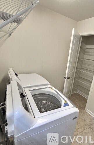 A white dishwasher is in a kitchen with a white wall and a white door.