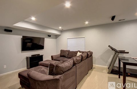A living room with a brown couch and a television on the wall.
