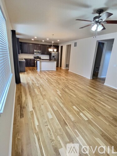 A spacious room with wooden flooring and a ceiling fan.