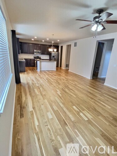 A spacious room with wooden flooring and a ceiling fan.