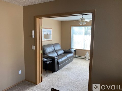 A living room with a black leather couch and a ceiling fan.