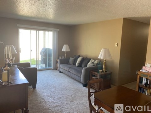A living room with a grey couch, a brown table, and a lamp.