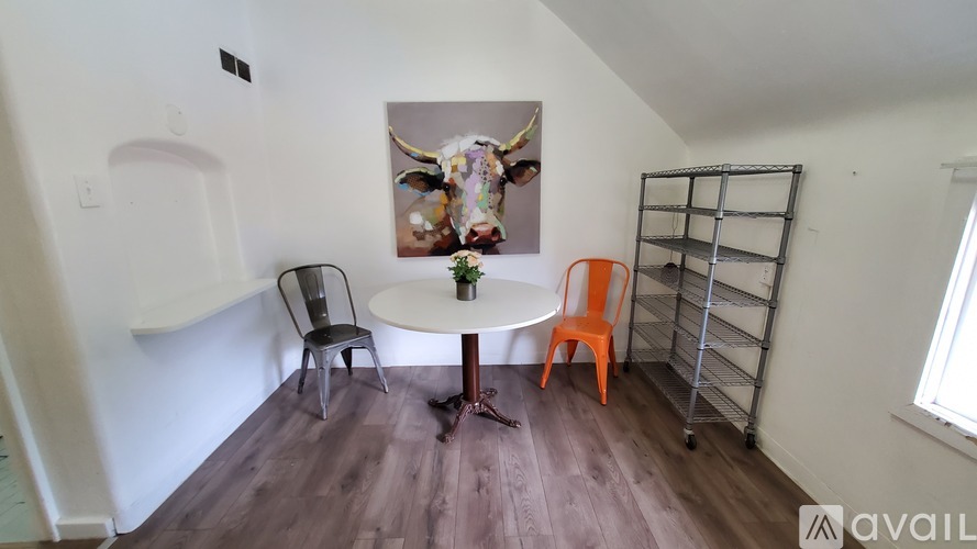 A room with a white table and chairs and a painting of a cow on the wall.