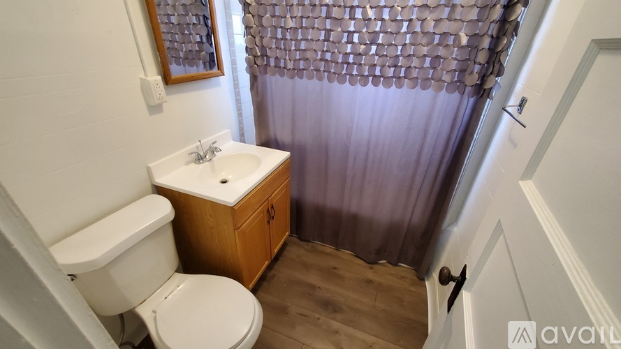 A small bathroom with a toilet, sink, and shower.